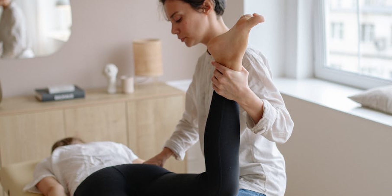 pexels-photo-5794025-5794025 Physiotherapist aiding a woman with leg exercises on a massage table for relaxation and therapy.
